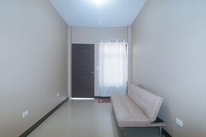 A hallway with a sofa, a door, and a window with curtains. - RedDoorz @ Aurea Apartelle (Iloilo City)