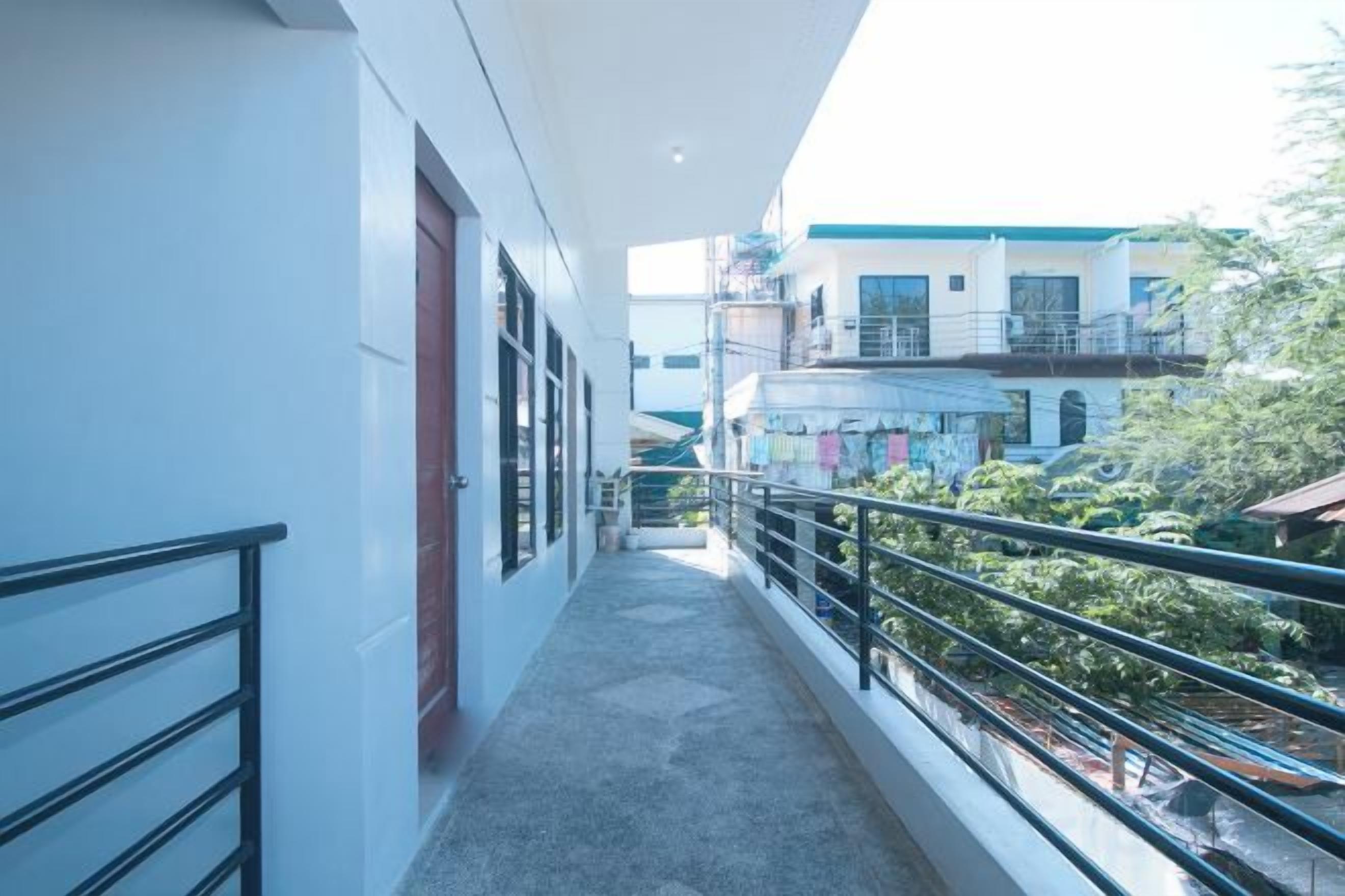 A narrow corridor with a balcony, leading to a building with multiple floors and balconies.