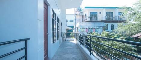 A narrow corridor with a balcony, leading to a building with multiple floors and balconies.