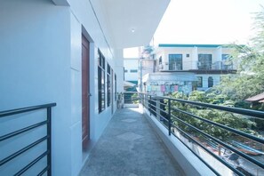 A narrow corridor with a balcony, leading to a building with multiple floors and balconies. - RedDoorz @ Aurea Apartelle (Iloilo City)