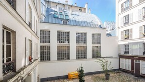 A courtyard with a building featuring large windows and a metal roof. - Blueground | Saint Vincent de Paul, view, nr Canal (Paris)