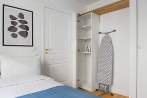 Une chambre à coucher avec un lit, une porte blanche, une armoire et une planche à repasser.