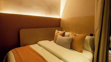 A modern hotel room with a large bed, a headboard, and a ceiling light fixture.