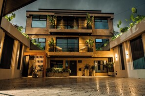Un bâtiment moderne à deux étages, doté d’une façade en briques, de grandes fenêtres et de nombreux balcons orn és de plantes.