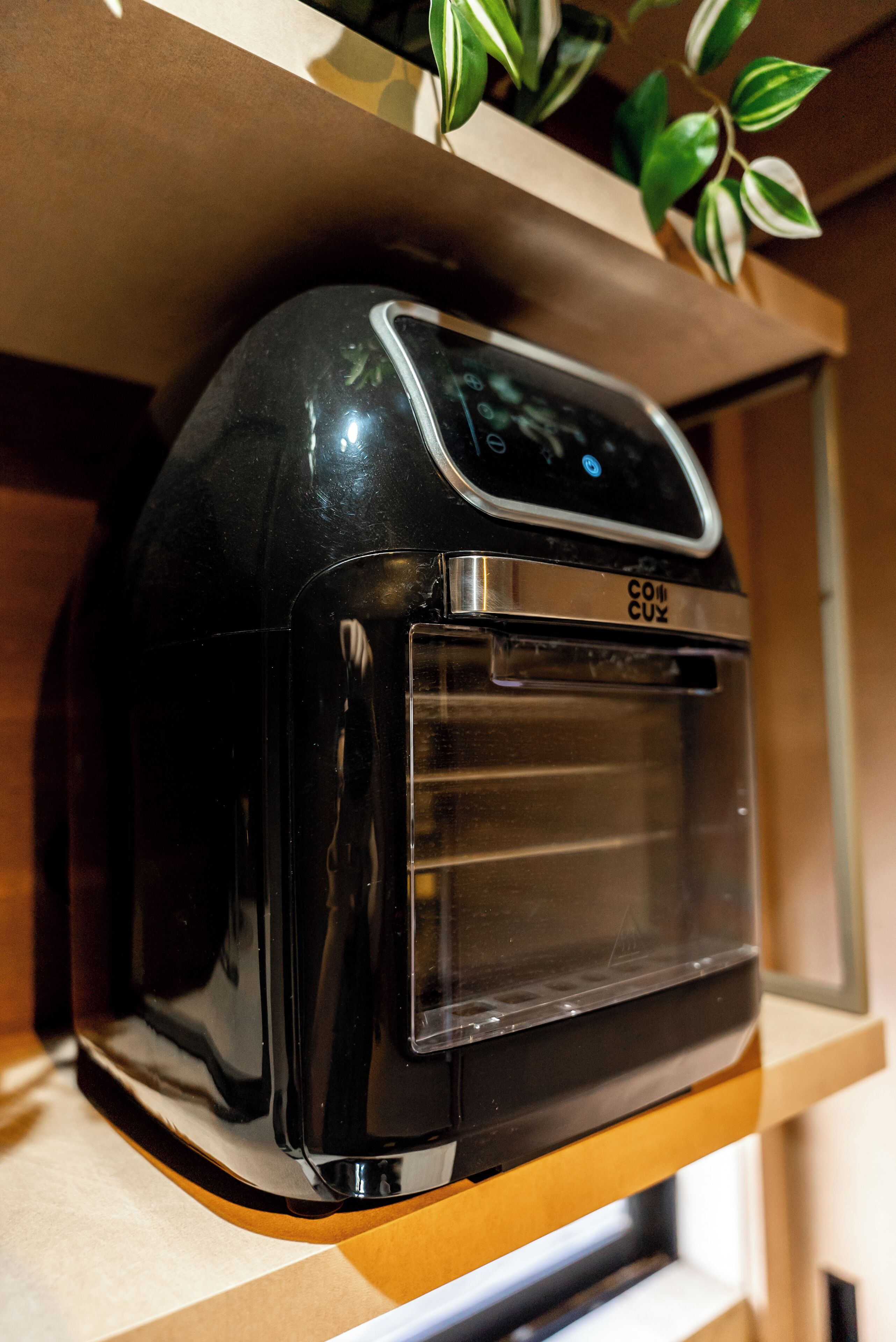 A black coffee maker with a digital display and a brand name on a wooden countertop.