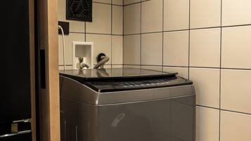 Una cocina compacta y moderna, con lavavajillas integrado, una pequeña encimera y una campana extractora de pared.
