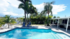 A swimming pool with lounge chairs, palm trees, and a covered patio area. - Waterfront Oasis w/heated Pool Dock Kayaks Fishing (New Port Richey)