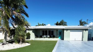 A single-story house with a garage, a well-maintained lawn, and a palm tree. - Waterfront Oasis w/heated Pool Dock Kayaks Fishing (New Port Richey)