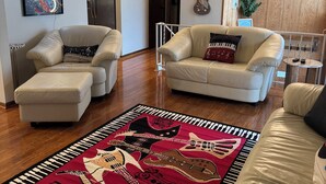 Salón con dos sofás color beige, un tapete con motivos de guitarra en rojo y negro, y una pared de madera con una decoración de guitarra.
