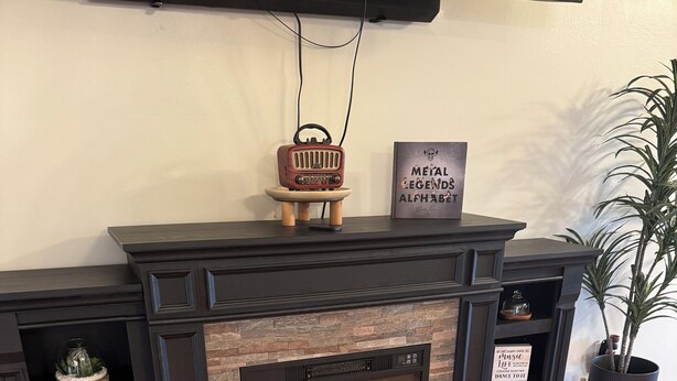 Una chimenea moderna con revestimiento de piedra, un televisor montado encima y elementos decorativos en la repisa.