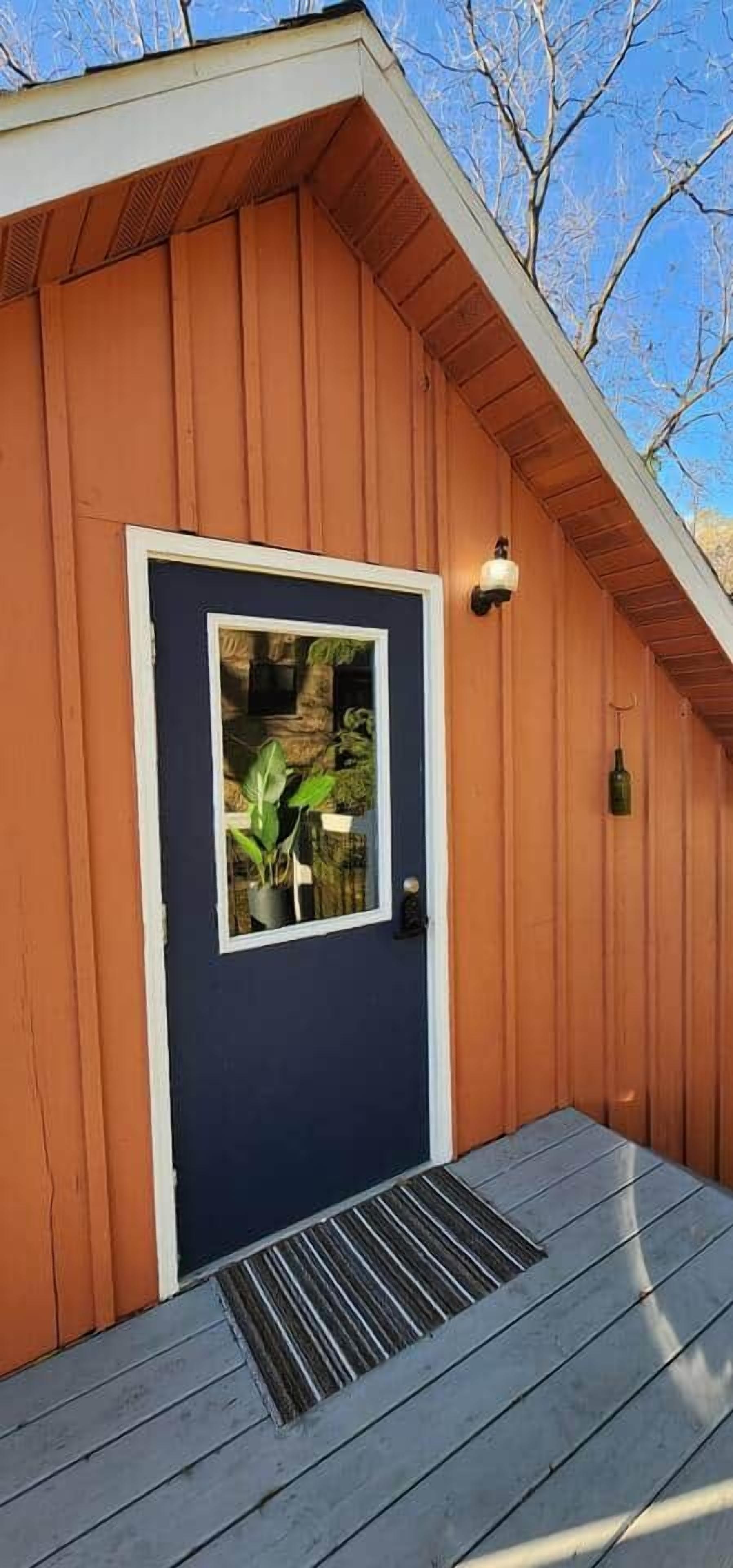 A wooden building with a dark blue door, a small window, and a light fixture above the door.