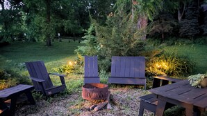 Un espace extérieur aménagé avec des chaises Adirondack, un foyer et une table.