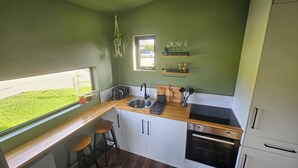 Una cocina compacta con ventana, con taburetes de bar, un fregadero, un tostador, un bloque de cuchillos y un horno.