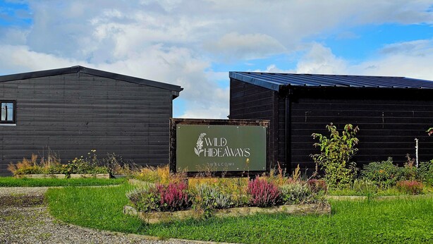 Un edificio rústico de madera con un letrero que dice “Wild Hideaways Welcome”.