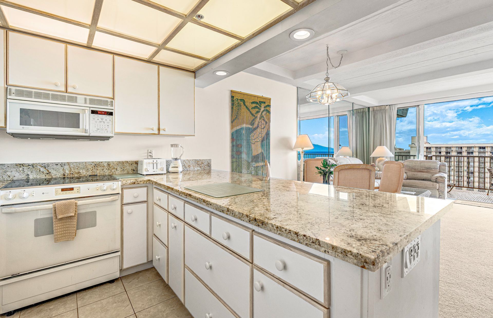 A modern kitchen with granite countertops, white cabinetry, a microwave, a toaster, and a stove.
