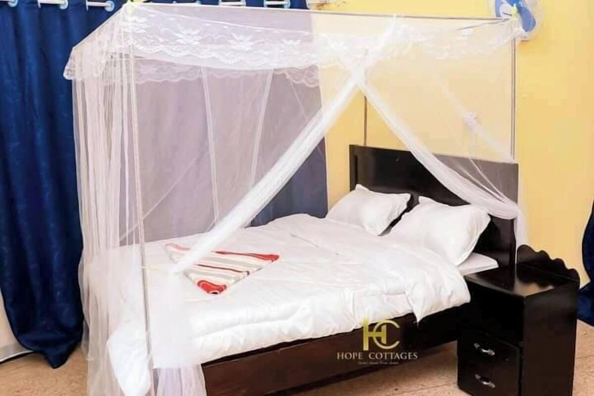 A bed with a white canopy, a bedside table, and a black nightstand.
