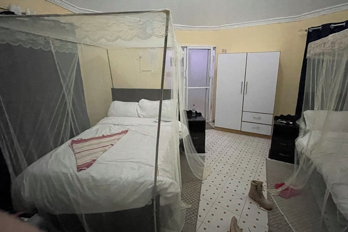 A hotel room with two beds, a wardrobe, and a small table.
