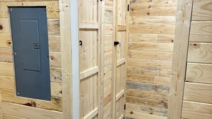 A wooden room with two doors, one with a dark panel and a small window, and a grey floor. - The Wild & Wonderful – Steps from Hatfield-McCoy Trails (Matewan)