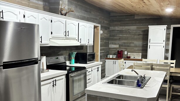 A modern kitchen with white cabinets, stainless steel appliances, and a central island. - The Wild & Wonderful – Steps from Hatfield-McCoy Trails (Matewan)