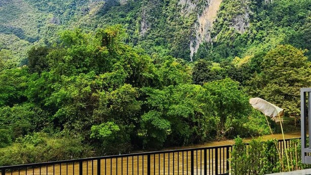 Una piscina amb vista a vegetació exuberante i muntanyes al fons.