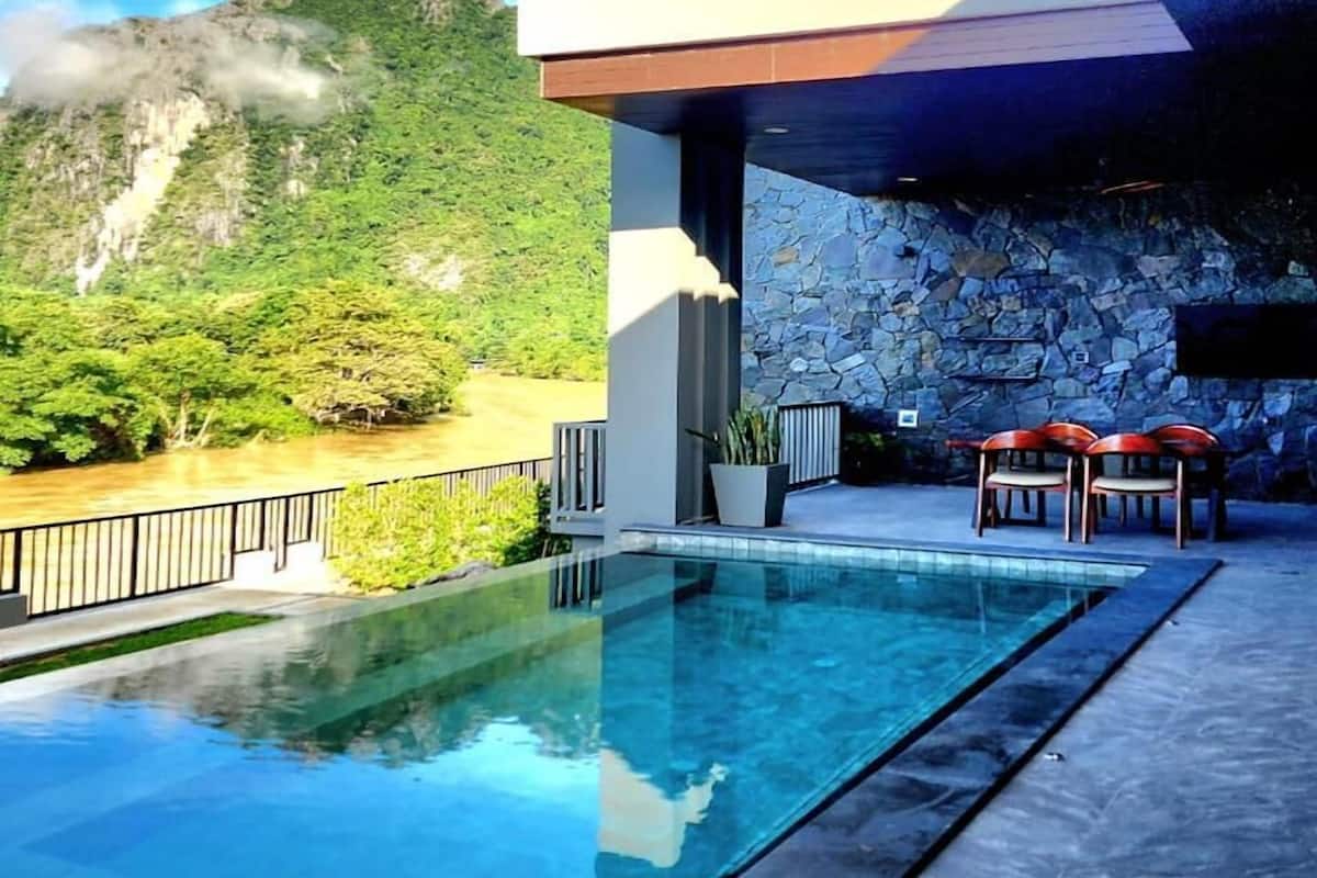 Ein moderner Poolbereich im Freien mit einer Steinmauer und Bergblick.