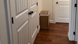 A hallway with wooden flooring and white doors with black handles. - Adorable 2-bedroom house with AC in charming Pryor (Pryor)