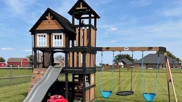 A playground with a slide, swings, and a multi-level wooden structure. - Adorable 2-bedroom house with AC in charming Pryor (Pryor)