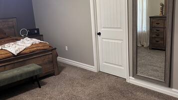 A bedroom with a bed, a bedside table, a mirror, and a ceiling fan.