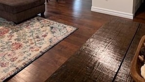 A living room with a brown sofa, a floral rug, and a dining area with a table and chairs. - Adorable 2-bedroom house with AC in charming Pryor (Pryor)
