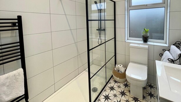 Un baño con ducha de vidrio, inodoro, lavamanos y ventana.