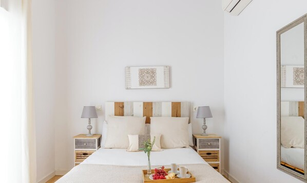 A neatly arranged bedroom with a large bed, two bedside tables with lamps, a tray of fruit and coffee, and a mirror on the wall. - El Escondite TriplexLiving4malaga (Málaga)