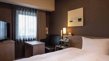 Una habitación de hotel con una cama grande, televisión, escritorio y una silla.