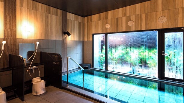 Ein modernes Badezimmer mit einem durch eine Glasscheibe abgetrennten Pool, Holzvertäfelung und Blick ins Grüne.