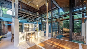 A spacious kitchen with a central island, large windows, and a view of greenery outside. - Twin House Ubud by Betterplace (Mas)