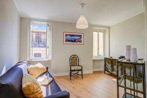 Una sala de estar con sofá, sillón, mesa y un cuadro en la pared.