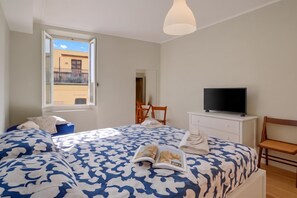 A bedroom with a bed, a television, a window, and a chair. - Armonia Centrale - Sanremo Apt for 4 with A/C, Sanremo, Italy (Sanremo)
