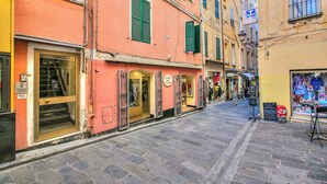 A narrow street with buildings on either side, featuring storefronts and a visible shop with a signboard.