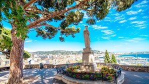 A statue in a circular plaza with a flower bed, surrounded by a stone wall and benches. - Cannes Center - 5min from Croisette & Pal, Cannes, France (Cannes)