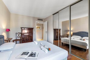 A hotel room with a large bed, a wooden dresser, a chair, a desk, and a mirror. - Cannes Center - 5min from Croisette & Pal, Cannes, France (Cannes)
