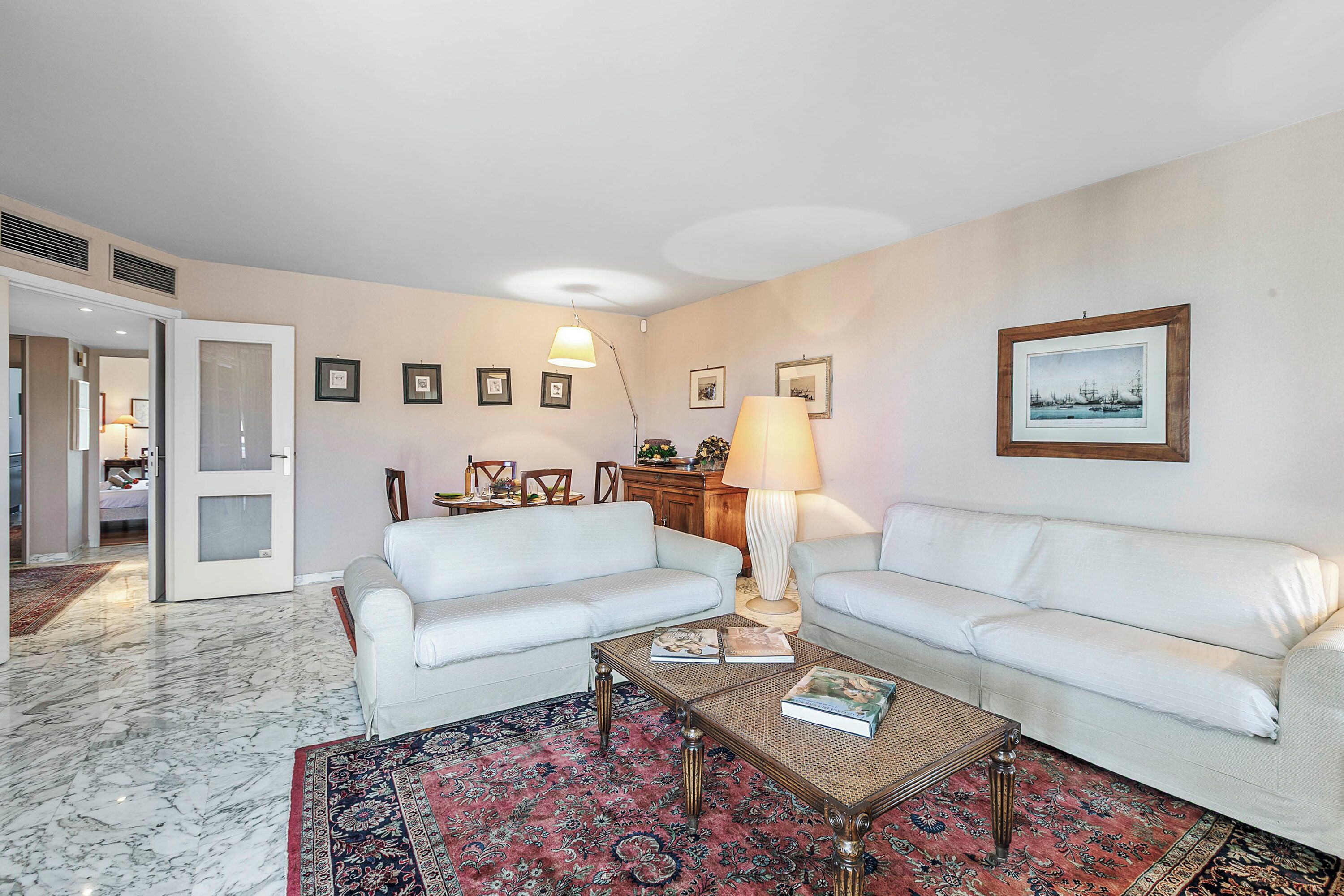 A living room with two white sofas, a coffee table, a patterned rug, and a framed picture on the wall.