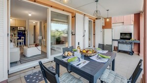Een eethoek met een tafel voor twee personen, een grill en een keuken op de achtergrond.