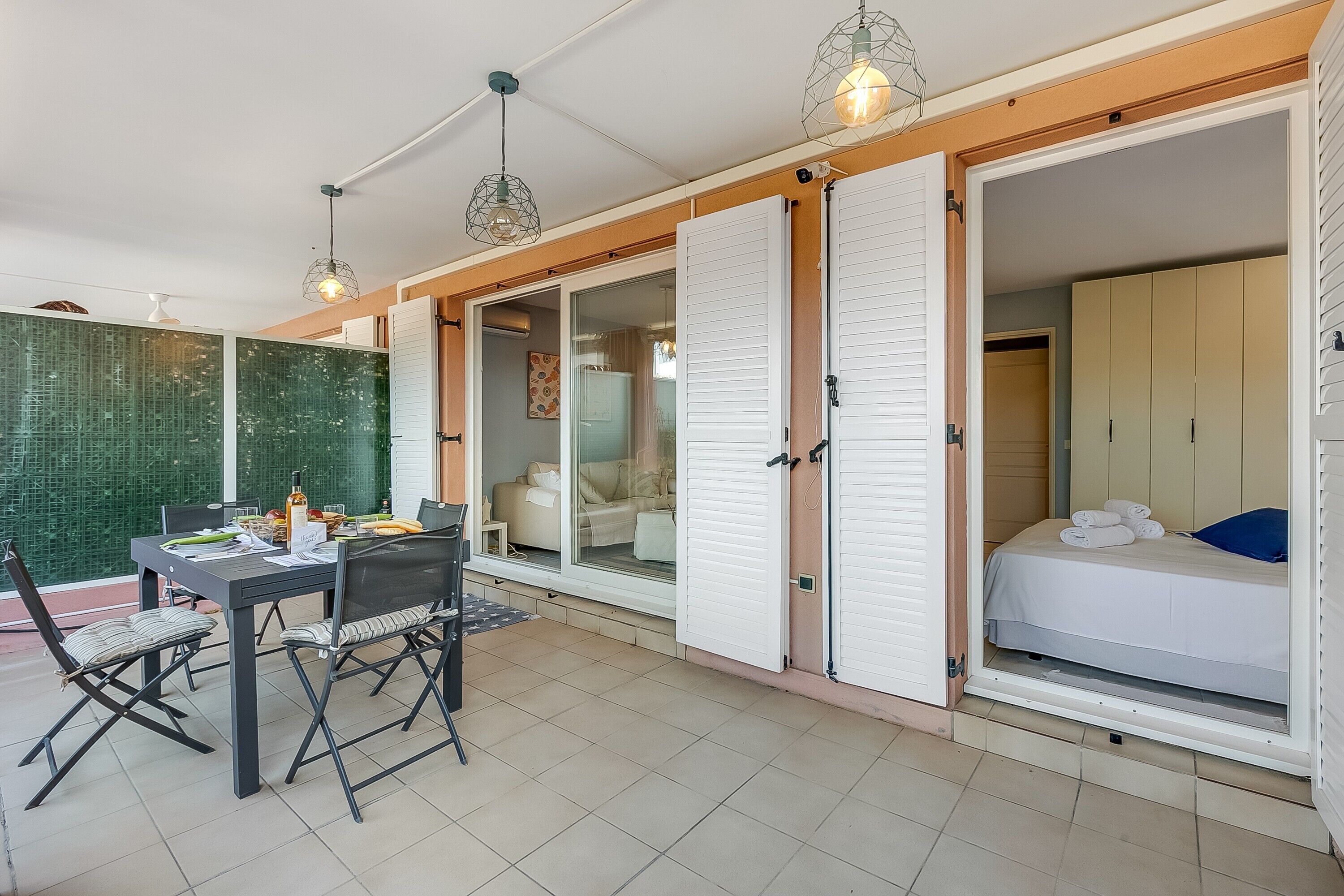 A room with a bed, a table with chairs, and a sliding door leading to another room.