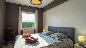 A bedroom with a bed, a window, a radiator, a bedside table, and a hanging rack. - Chez David by Interhome (Kersaint-Plabennec)