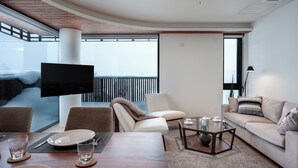 A modern living room with a flat-screen TV, comfortable seating, a dining area, and a large window with a view. - Yotei Dream One (Kutchan)