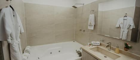 A modern bathroom with a large bathtub, a sink, and a mirror. There are towels and a sign on the wall.