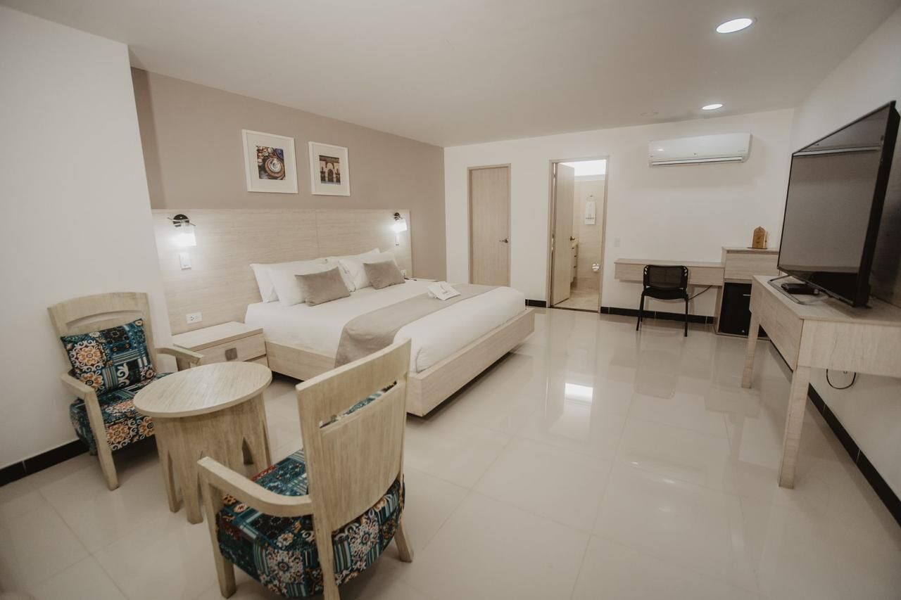 Una habitación de hotel con cama, mesitas de noche, escritorio, silla y televisión.