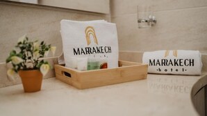 A bathroom with a wooden tray holding toiletries, a potted plant, and a towel with "MARRAKECH hotel" printed on it. - Noma Hotel And Rooftop (Cali)