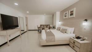 A modern hotel room with a large bed, bedside tables, a TV, and a sofa. - Noma Hotel And Rooftop (Cali)
