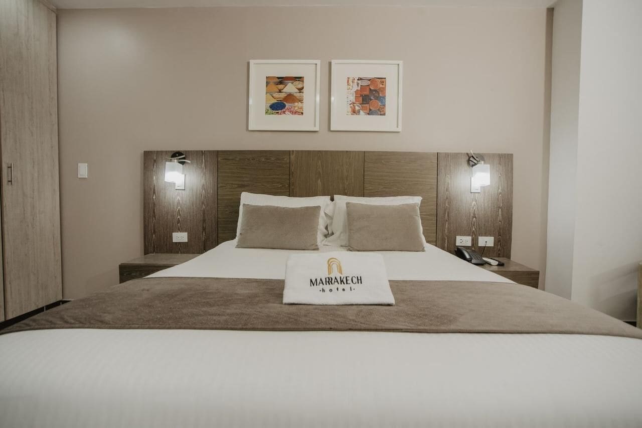 Ein Hotelzimmer mit einem großen Bett, zwei Nachttischen, einem hölzernen Kopfteil und zwei Wandleuchten.