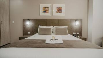 A hotel room with a large bed, two bedside tables, a wooden headboard, and two wall-mounted lights.